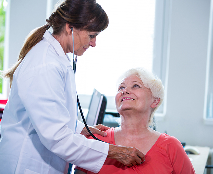 A doctor is examining an older woman 's chest.