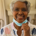 A woman wearing a face mask and smiling.