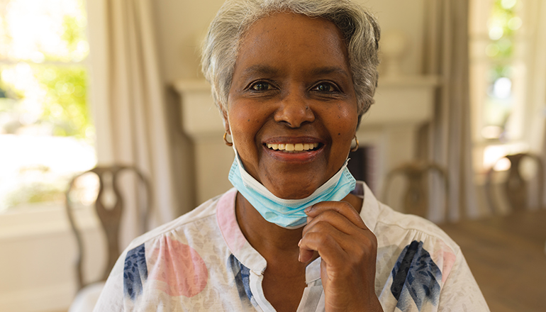 A woman wearing a face mask and smiling.