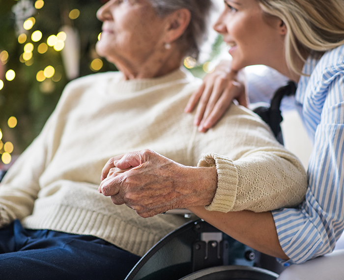 A woman holding the hand of an older person.