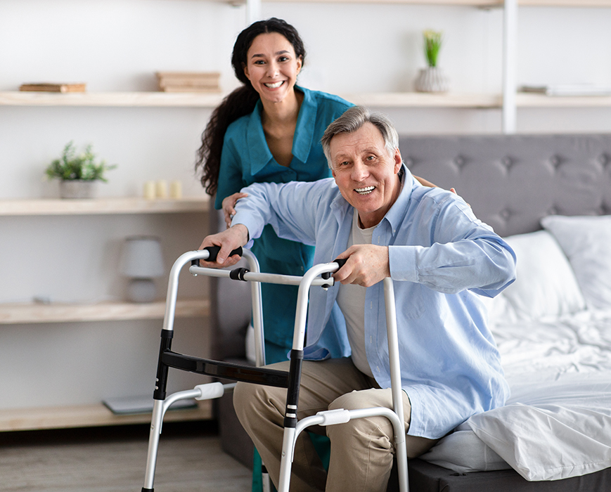 A man and woman sitting on the bed with their walker.