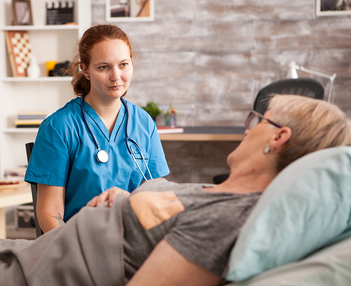 A nurse talking to an older man in bed.